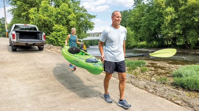 Couple holding a kayak walking to river