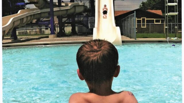 kid looking on to a swimming pool with a huge slide
